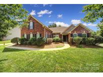 Charming brick home with lush lawn, blue sky, manicured landscaping, and a welcoming walkway at 2000 Taney Way, Indian Land, SC 29707