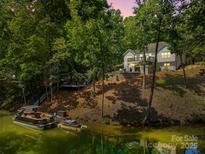 Lakefront home featuring a private dock and a lakeside setting surrounded by lush greenery at 402 Wildlife Rd, Troutman, NC 28166