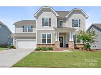Charming two-story home featuring a manicured lawn, attached garage, and a welcoming front porch at 4116 Tory Path Rd, Waxhaw, NC 28173