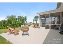 Covered patio with wicker seating and a beautiful lawn with trees in the background at 4116 Tory Path Rd, Waxhaw, NC 28173