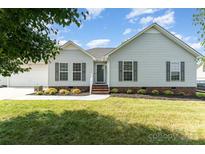 Charming single story home featuring manicured lawn, landscaped garden beds, and stylish shutters at 614 W Peeler St, Salisbury, NC 28146