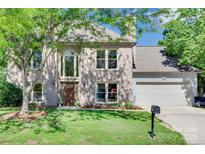 Charming brick two-story home with a well-manicured lawn and mature trees at 12004 Woodholm Ct, Tega Cay, SC 29708