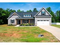 Charming home featuring gray siding, a two-car garage, a well-manicured lawn, and delightful landscaping at 205 Spring Creek Dr, Mount Holly, NC 28120