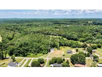 An aerial view of a wooded lot with a charming house nestled among lush trees and greenery at 237 Mariposa Rd, Stanley, NC 28164