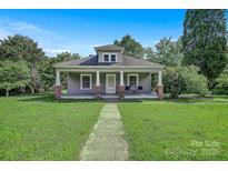 Charming home featuring a welcoming front porch with classic column details and lush lawn at 2417 Statesville Blvd, Salisbury, NC 28147