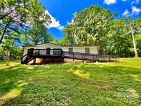 Charming ranch-style home with black trim, inviting deck and ramp access on a lush, tree-lined lot at 325 Scaley Bark Dr, Salisbury, NC 28147