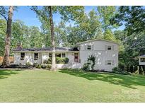 Charming white two-story home with a well-manicured lawn and beautiful landscaping at 5611 Robinhood Rd, Charlotte, NC 28211