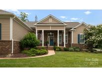 Charming home featuring manicured landscaping, a brick facade, and a welcoming front porch with white pillars at 6506 Jepson Ct # 349, Charlotte, NC 28214