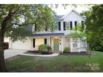 Charming two-story home with light siding, black shutters, green door, and well-maintained landscaping at 11407 Lenswood Ct, Charlotte, NC 28214