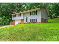 Split-level home with a front yard and a one-car garage, featuring a brick base and gray siding at 1309 Poplar Cir, Newton, NC 28658