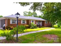 Charming one-story brick home featuring a well-maintained lawn and mature trees at 405 Wesley Heights Dr, Albemarle, NC 28001