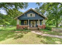 Charming blue home with inviting front porch and brick accents, surrounded by lush greenery at 6206 Hunter Ave, Charlotte, NC 28262