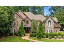 Stunning stone and brick home featuring mature landscaping and a meticulously maintained lawn at 6565 Robin Hollow Dr, Mint Hill, NC 28227