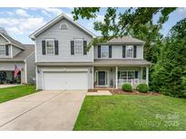 Charming two-story home featuring a welcoming front porch and a well-maintained lawn with a two car garage at 7218 Cascading Pines Dr, Fort Mill, SC 29708