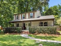 Charming two-story home with a inviting covered porch, lush landscaping, and a well-manicured lawn at 911 Munday Ct, Charlotte, NC 28270