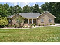 Charming brick home featuring a well-manicured lawn and inviting front porch with meticulous landscaping at 9117 Castle Garden Ln, Charlotte, NC 28215