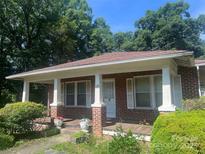 Charming brick home with a covered front porch, white columns, and lush landscaping at 226 S Morrow Ave, Albemarle, NC 28001