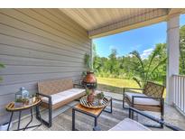 Inviting covered patio with stylish seating, outdoor rug, and views of the lush backyard at 336 Secretariat Dr, Iron Station, NC 28080