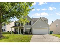 Charming two-story home with a well-manicured lawn, a two-car garage, and a covered front porch at 5822 Parkstone Dr, Matthews, NC 28104