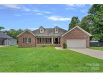 Charming brick home featuring a manicured front lawn, attached two-car garage and inviting front porch at 7478 Pine Ridge Dr, Denver, NC 28037