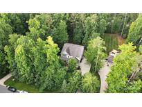 An aerial view of a house surrounded by lush green trees, a large driveway, and a well-manicured lawn at 8214 Aspen Ct, Mint Hill, NC 28227