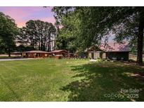 Expansive green lawn with a variety of buildings and mature trees, offering a serene, estate-like setting at 835 Holshouser Rd, Rockwell, NC 28138