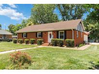 Charming brick home with manicured lawn, lush shrubbery, and welcoming front entrance at 1219 Flowe Dr, Matthews, NC 28104
