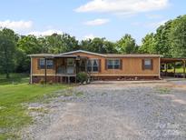 Charming single-Gathering home featuring a spacious front yard and a covered parking area on a sunny day at 130 Benton Rd, Kings Mountain, NC 28086