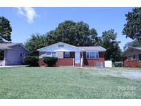 Charming brick home with a well-maintained lawn and mature trees on a sunny day at 1926 Eastway Dr, Charlotte, NC 28205