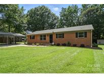 Charming single-story brick home featuring a spacious front yard with mature trees and a convenient carport at 2705 Lowell Bethesda Rd, Gastonia, NC 28056