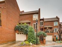 Charming brick townhome featuring lush landscaping, attached garage, and wrought iron gate at 311 Settlers Ln, Charlotte, NC 28202