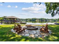 Inviting lakefront fire pit with stone surround and Adirondack chairs perfect for relaxing by the water at 4485 River Oaks Rd, Lake Wylie, SC 29710