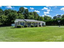 Charming brick home with a well-manicured lawn, mature trees, and a long driveway, set under a sunny sky at 50 Isenhour Park Rd, Taylorsville, NC 28681