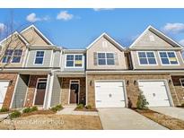 Charming townhomes with stone accents, attached garages, and well-manicured lawns offer modern living at 6274 Tea Olive Dr # 237, Harrisburg, NC 28075