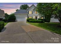 Charming two-story home with a well-manicured lawn and inviting curb appeal at dusk at 9954 Mitchell Glen Dr, Charlotte, NC 28277