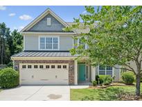 Charming two-story home featuring a teal front door, well-manicured lawn, and a brick-accented garage at 10009 Community House Rd, Charlotte, NC 28277