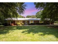 Charming one-story brick home features a lush green lawn and mature trees in a serene setting at 114 Huffstetler Rd, Gastonia, NC 28056