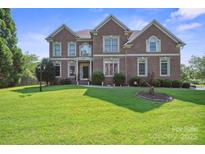 Stately brick home with a well-manicured lawn and mature landscaping at 12004 New Bond Dr, Huntersville, NC 28078