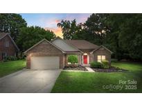 Charming brick home with a well-manicured lawn, attached garage, and a welcoming red front door at sunset at 14747 Pomerol Ln, Pineville, NC 28134