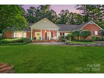 Beautiful brick home featuring a large front yard and covered porch with yellow front door at 307 Dogwood Dr, Mount Holly, NC 28120