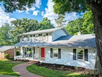 Charming two-story home with a welcoming front porch, painted brick, a red door, and beautifully landscaped yard at 310 25Th Nw Ave, Hickory, NC 28601