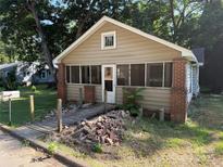 A front view of the home with a partially screened-in porch and some missing bricks at 310 E Division Ave, East Spencer, NC 28039