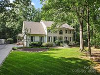 Charming two-story white brick home featuring mature trees, lush lawn and professionally landscaped flower beds at 3717 Bounty Ct, Matthews, NC 28104