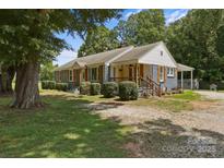 Charming single-story home featuring a welcoming front porch, mature trees, and stylish shutters at 435 Stirewalt Rd, China Grove, NC 28023
