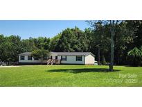 Single story home with front porch nestled amongst mature trees on a large lot at 4688 Taxahaw Rd, Lancaster, SC 29720