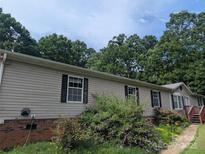 A view of the home's exterior with shutters, landscaping, and mature trees at 5324 Weblee Ct, Kings Mountain, NC 28086