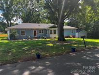 Charming home with mature trees, blue paint, and manicured lawn at 6109 Cora St, Charlotte, NC 28216