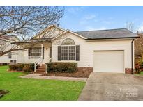 Charming single-story home with white siding, a well-manicured lawn, and an attached single-car garage at 828 Saint Andrews Pl, Concord, NC 28025