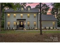 Beautiful two story white brick home with black trim, a dark roof, and manicured lawn at 9830 Spring Harvest Dr, Mint Hill, NC 28227