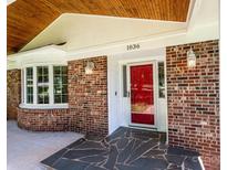 Inviting brick home featuring a red front door, black slate entryway, and a warm, wood-paneled porch ceiling at 1036 11Th Street Circle Nw Dr, Hickory, NC 28601